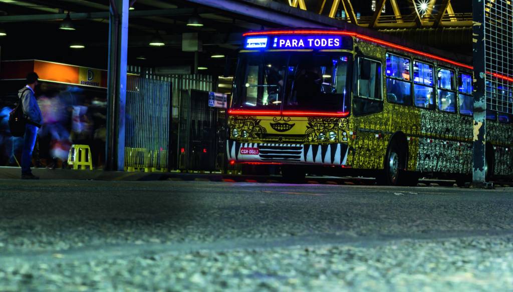2ZozimaOnibus.jpg Ônibus de lataria coberta por ilustrações amarelas andando na rua. No visor, está escrito