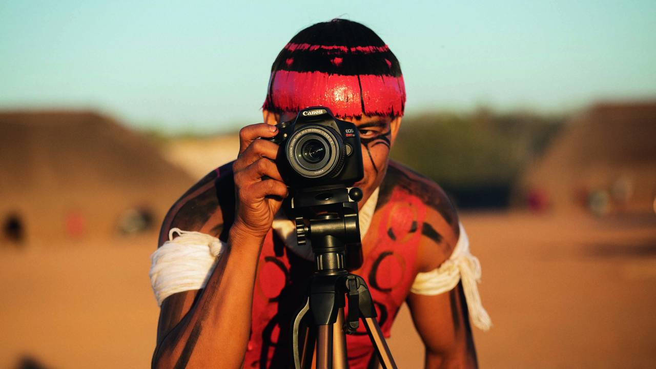 Integrante do Coletivo Kuikuro de Cinema se posiciona atrás de uma câmera