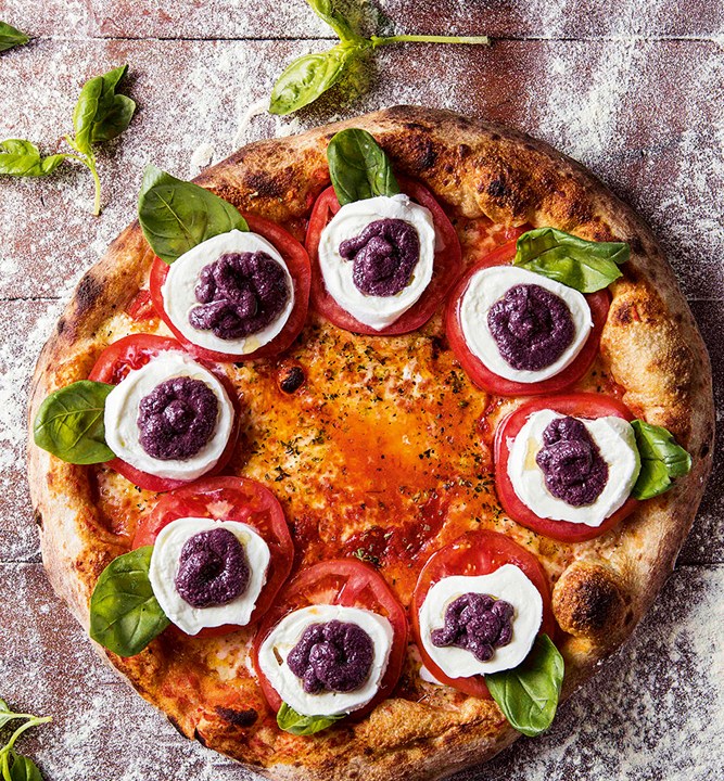 Pizza caprese Bráz com manjericão, mussarela de búfala, rodelas de tomate caqui e pesto de azeitona preta