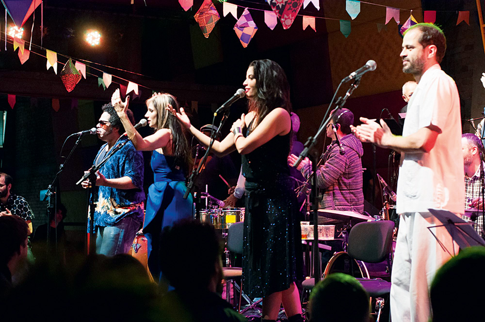 Imagem mostra pessoas em palco, cantando
