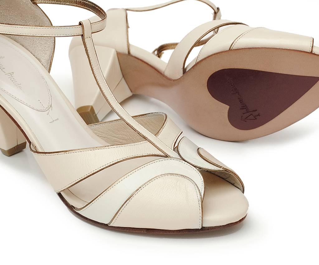Linha noivas Ju Bicudo, sapatos Janja (1) Par de saltos altos brancos com uma das solas mostrando desenho de coração vermelho.