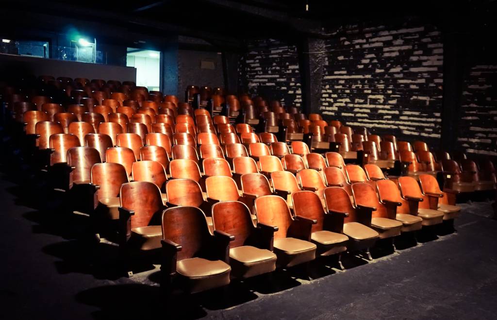 Teatro Paiol Cultural (Mark Aichholzer-Divulgação) (3) Foto exibe assentos de couro alinhados em sala de teatro iluminada.