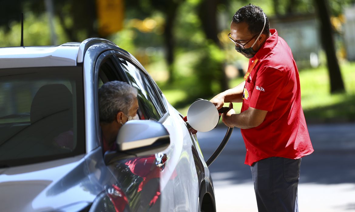 Senhora abastece o carro em posto de combustível, gasolina