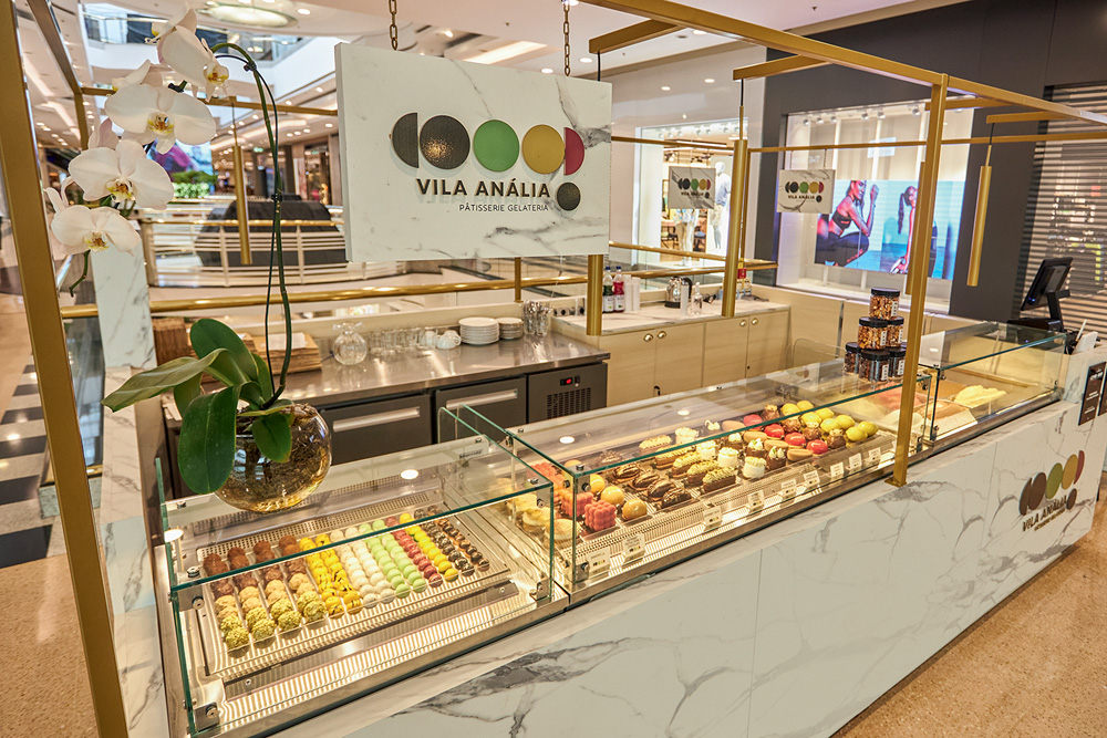 balcão de doces onde se lê Vila Anália Patisserie em um banner
