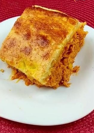 Torta de frango maionese farinha Kwai Prato de porcelana branca sobre superfície vermelha com um pedaço de torta de frango dourada