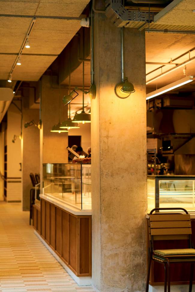 Ambiente Le Jazz Boulangerie Ambiente interno, com balcão envidraçado e luz amarela