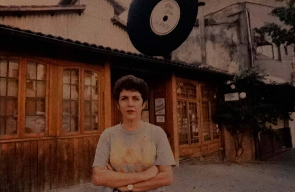 Café Piu Piu Silvia Galant Imagem mostra mulher de braços cruzados em frente a fachada de bar