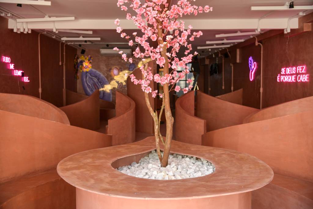 FOTOS PAULO SANTOS. Foto de ambiente com árvore rosa no centro de banco coletivo e paredes curvas em drywall.