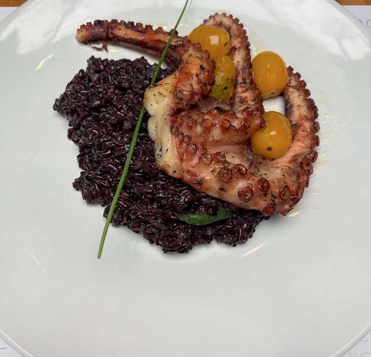 Prato de porcelana branca com tentáculos de polvo e arroz negro