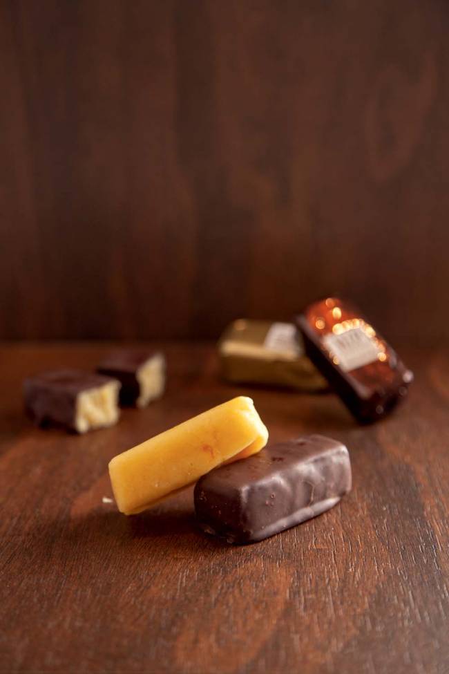Marzipan de laranja com raspas_3.jpg close em duas barrinhas de marzipã. Há outras barrinhas ao fundo da imagem, desfocadas