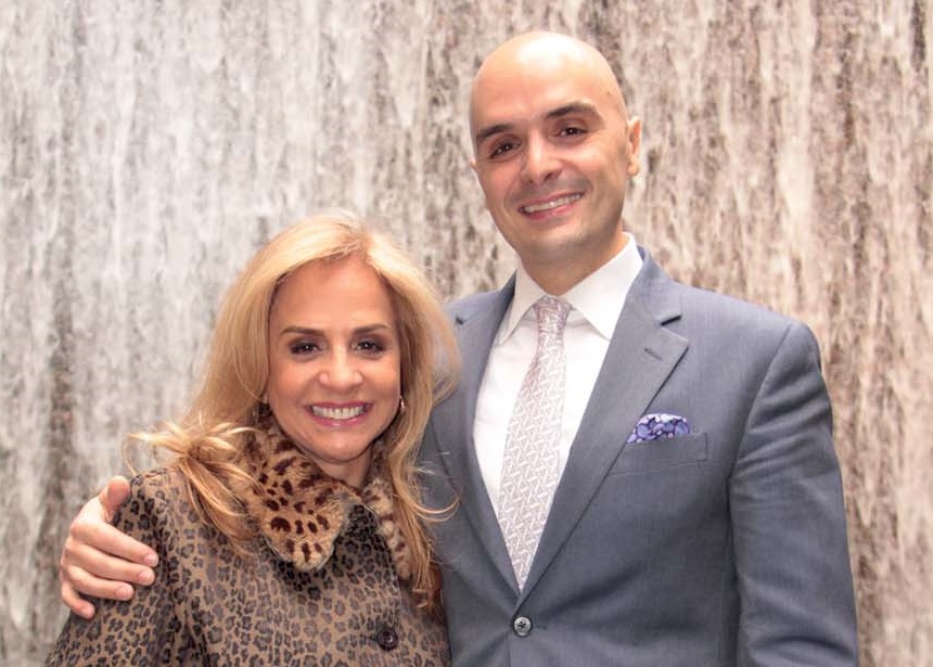 Foto mostra Yara e Frederico, abraçados, em fundo prata, usando roupas sociais