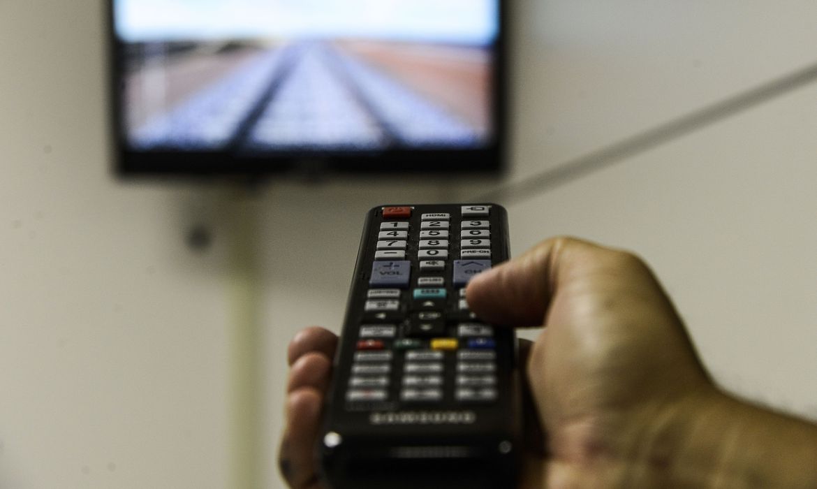 Pessoa apontando controle para televisão