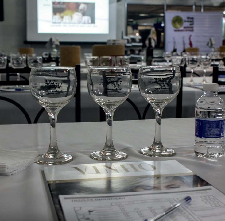 Imagem de mesa com caderneta, caneta e taças para degustação