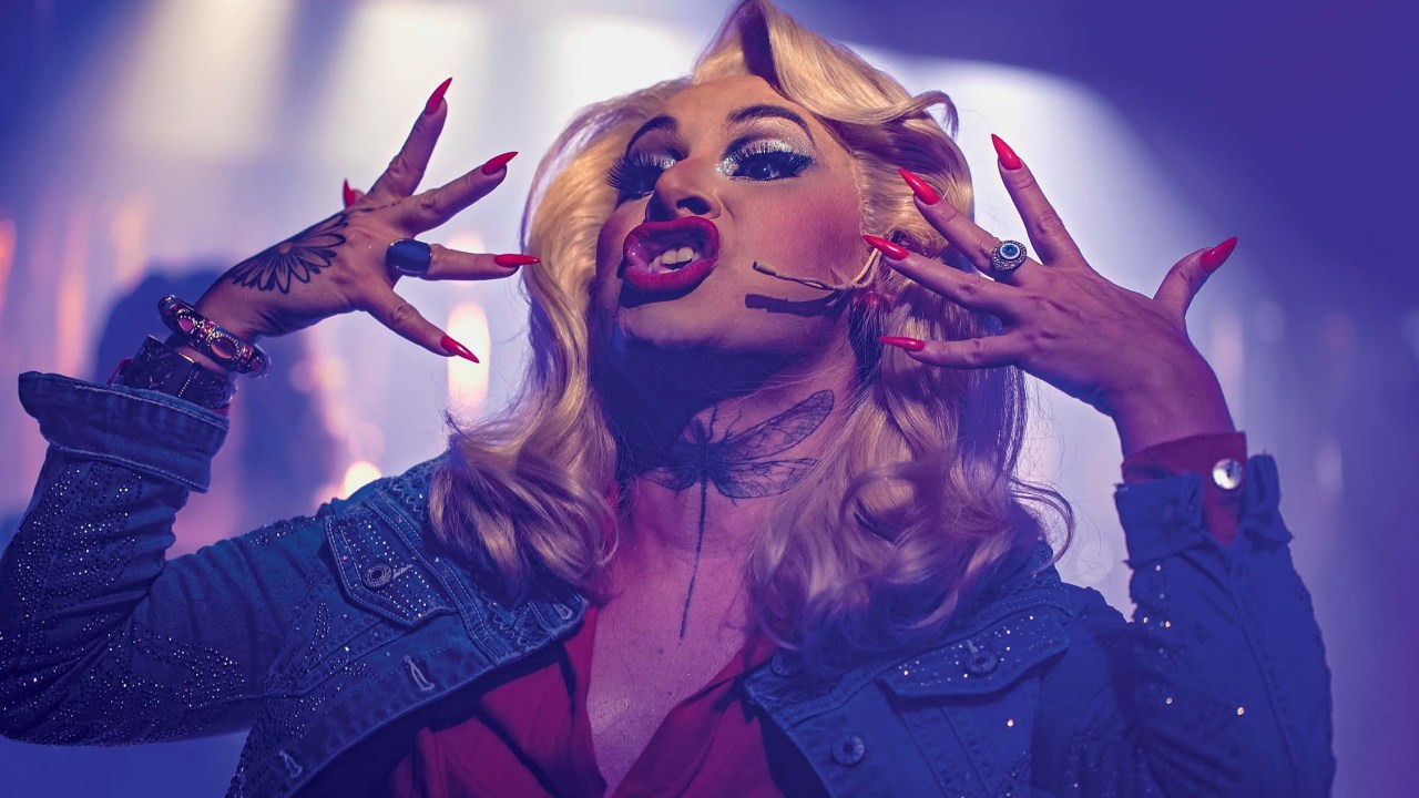 Mulher loira canta com as mãos perto da face