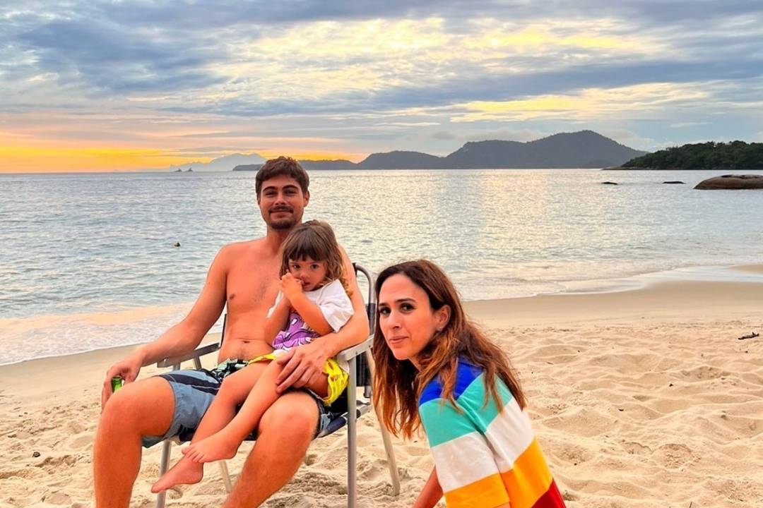 Casal e criança em praia no pôr do sol