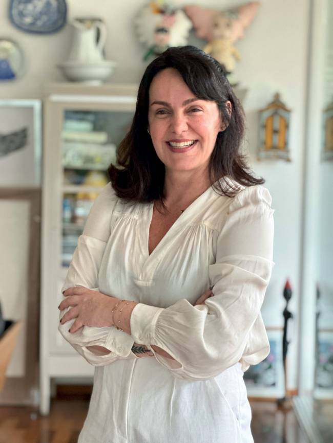 Carolina Delboni – Pedro Brandão.jpeg Carolina, de roupa branca, braços cruzados e sorrindo