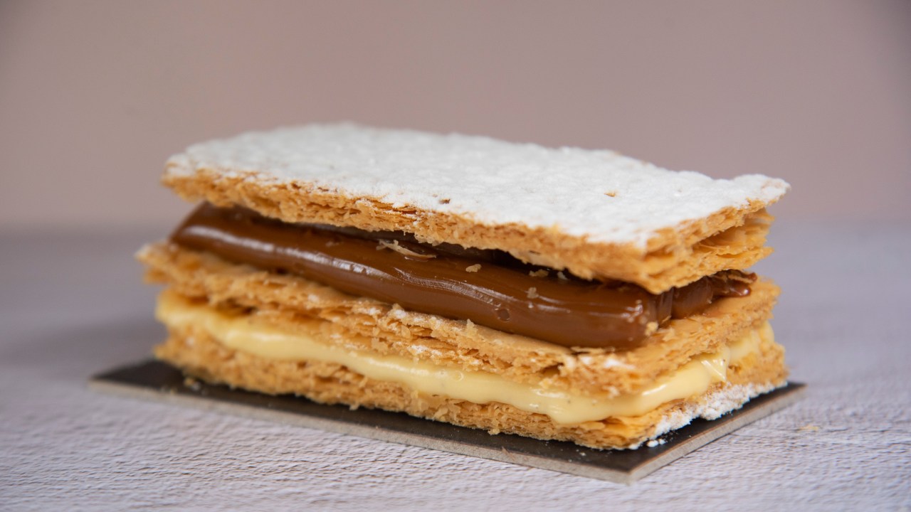 Massa crocante com duas camadas de creme, sendo que uma delas é de doce de leite. Cobertura de açúcar.
