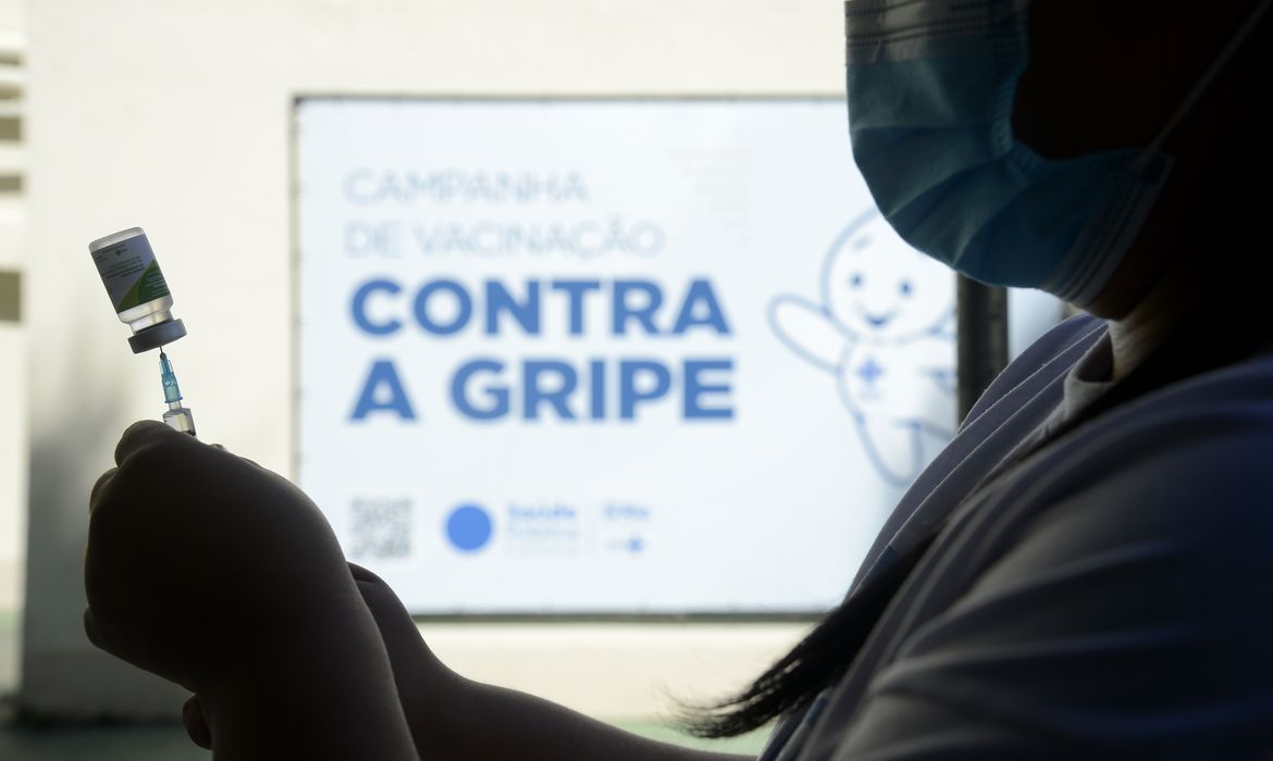 enfermeira de máscara segurando uma vacina
