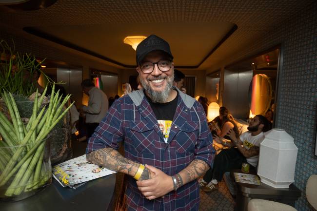 Homem sorrindo encostado em balcão de bar.