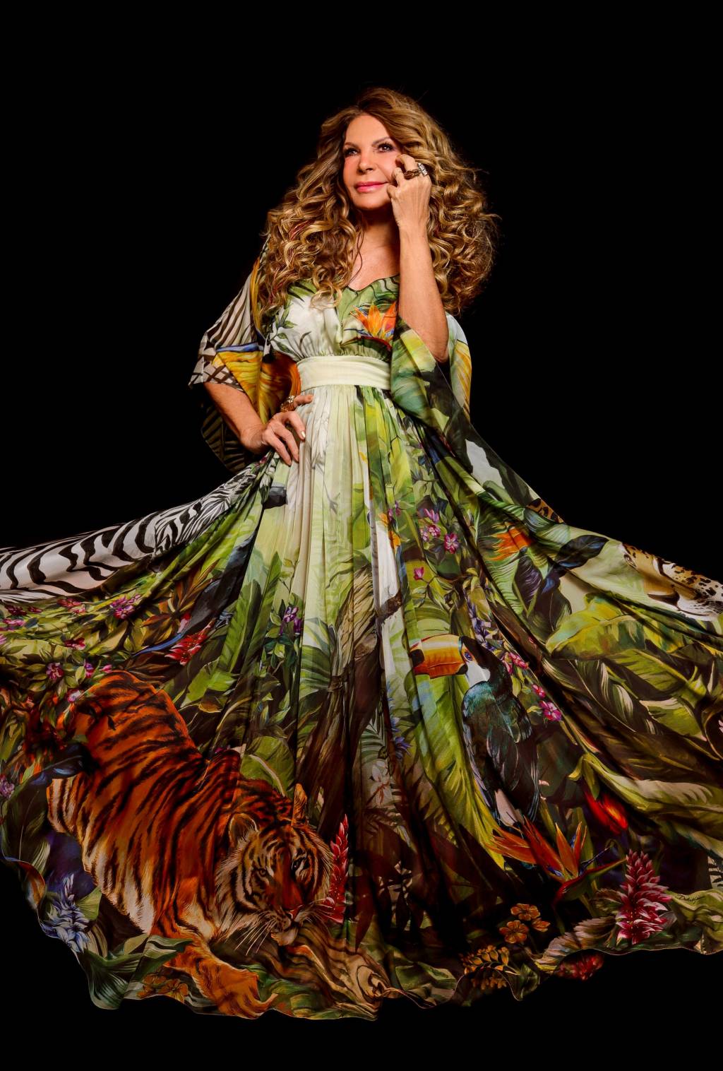 9 – Elba Ramalho (Lucas Menezes-Divulgação) Retrato de Elba Ramalho, mulher sorridente de cabelos encaracolados loiros. Veste um longo vestido estampado nas cores laranja e verde.
