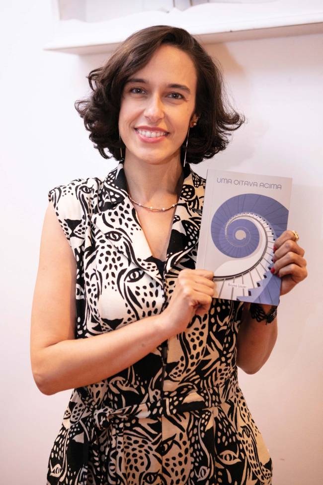 Bruna Lauer Mulher branca segurando livro em mãos.