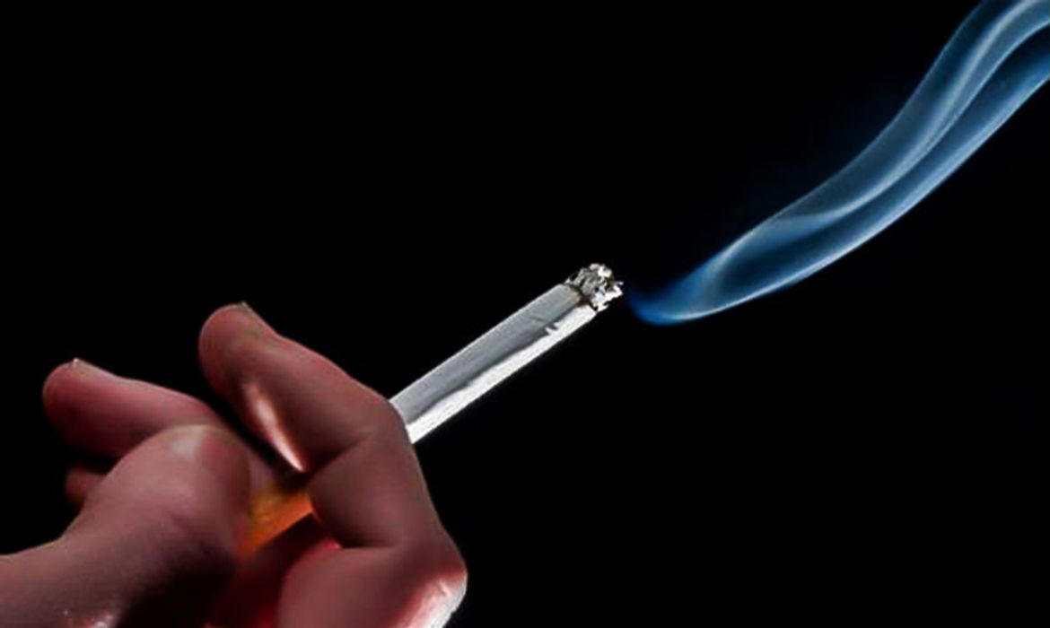 uma mão segurando um cigarro aceso