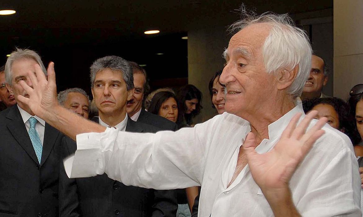 o dramaturgo zé celso gesticulando e outros homens parados ao fundo