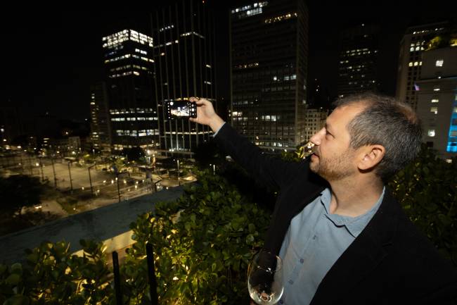 os mais amados de sp 2023 Imagem mostra homem tirando foto do Vale do Anhangabaú com celular