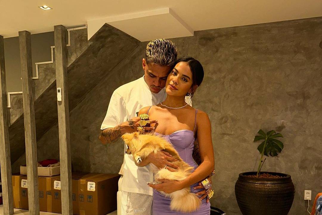 Bella Campos e MC Cabelinho abraçados enquanto bella segura um cachorrinho peludo no colo