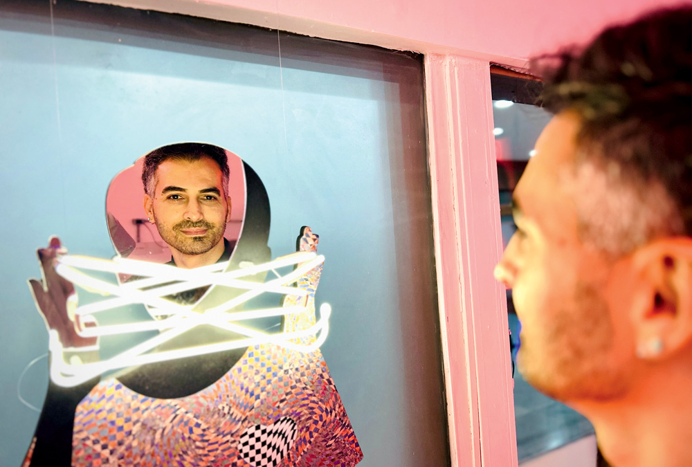 ANDREALMEIDA_GALERIANEON_4.jpg Homem branco de barba encara um espelho adornado por neons.