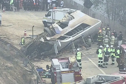 um ônibus capotado no meio da estrada com bombeiros ao redor