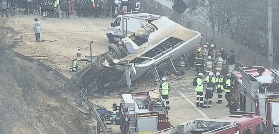 um ônibus capotado no meio da estrada com bombeiros ao redor