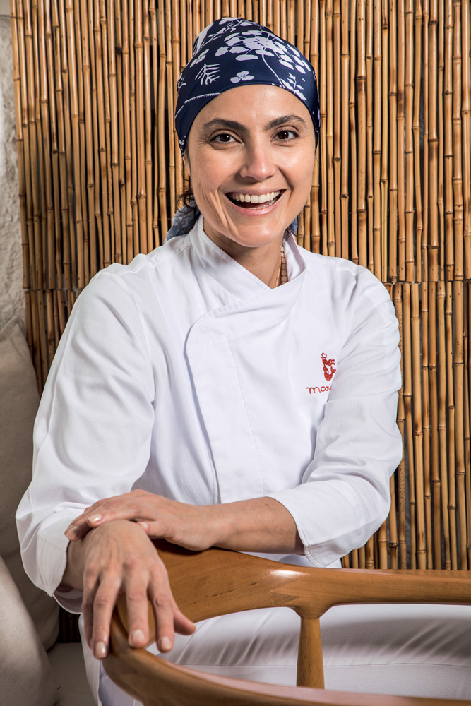 Myk – Mariana Fonseca Chef sentada de dólmã e lenço azul na cabeça.