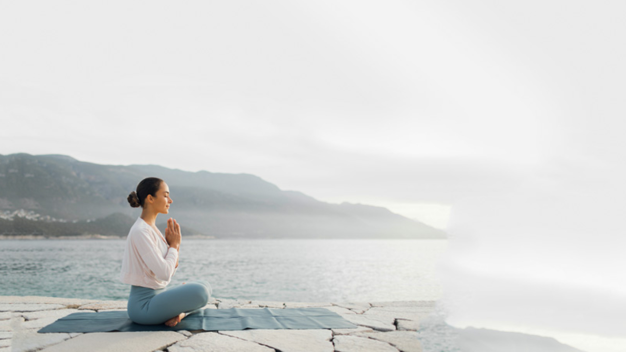Mulher sentada meditando em pedra beira-mar.