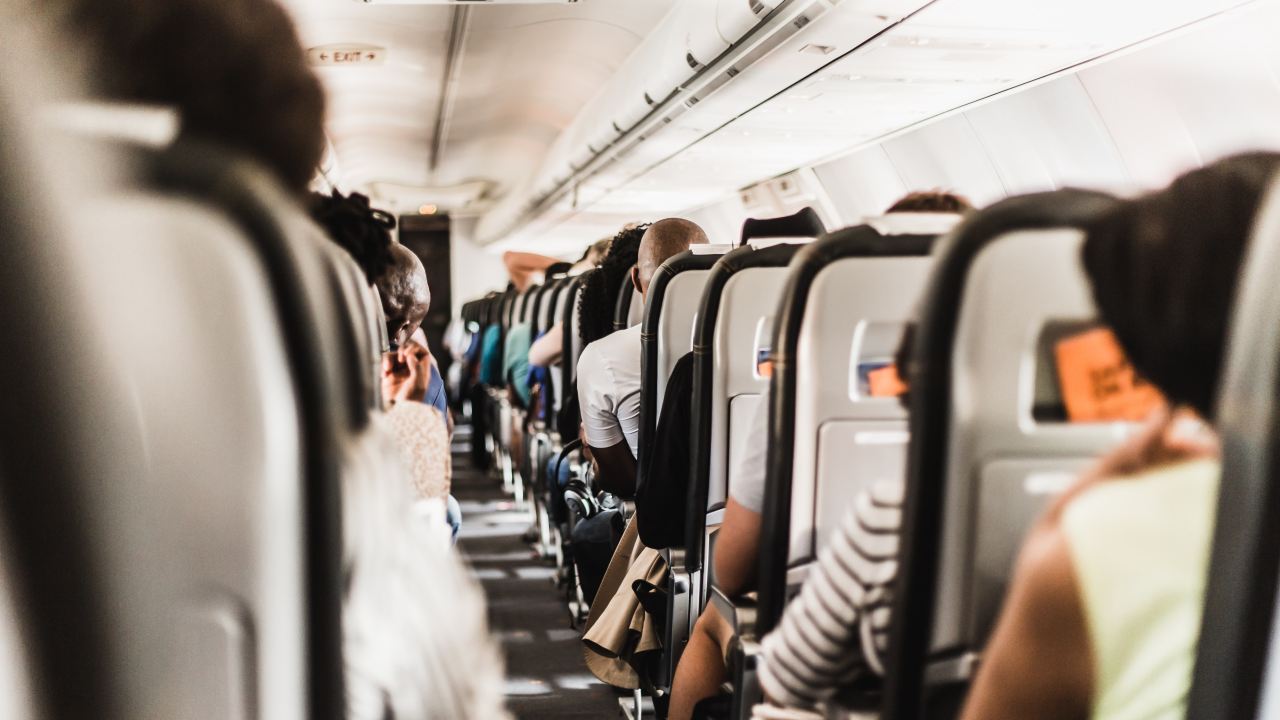 um avião por dentro. pessoas sentadas nas poltronas.