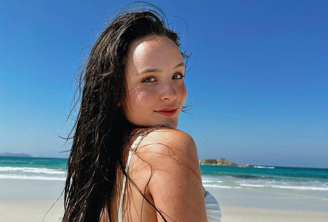 uma mulher branca de biquini e cabelos molhados na praia
