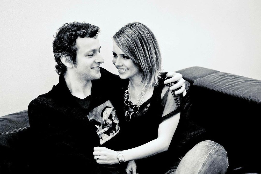 o casal está sentando em um sofá, ambos sorriem