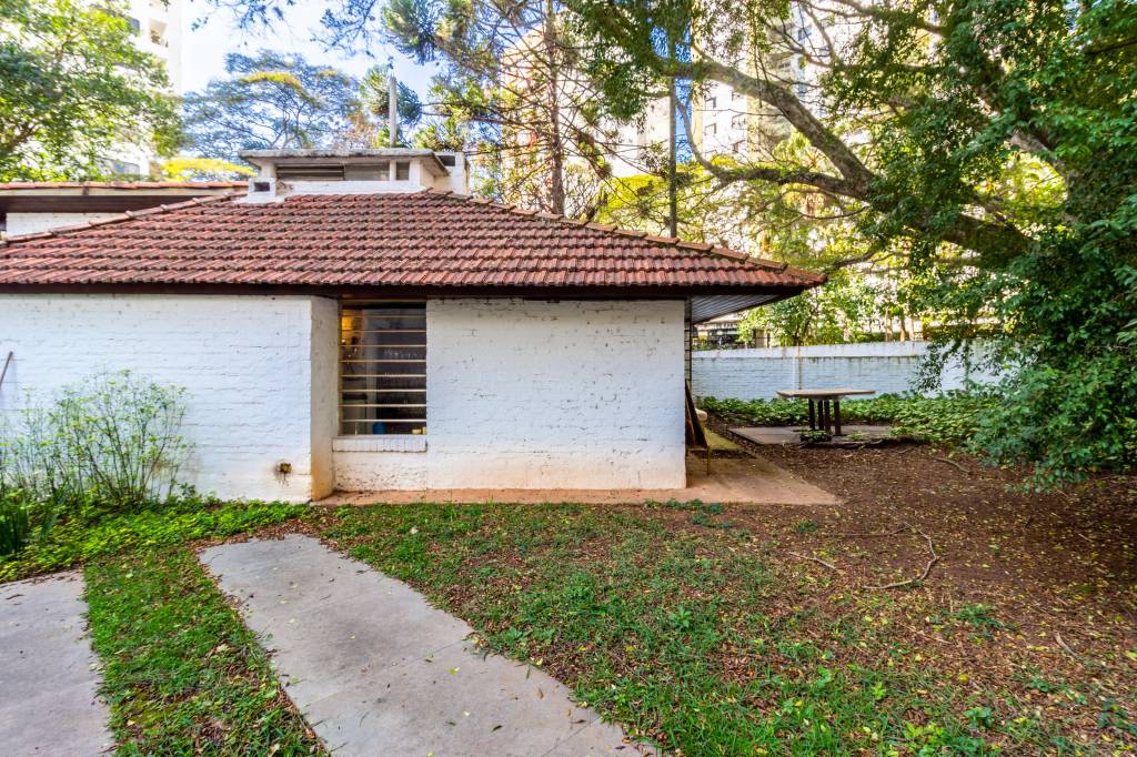 Casinha de Vilanova Artigas – Campo Belo – 1942 – @orafadandrea Casinha branca simples com telhado marrom aparece à esquerda em área com gramado e caminho de cimento.
