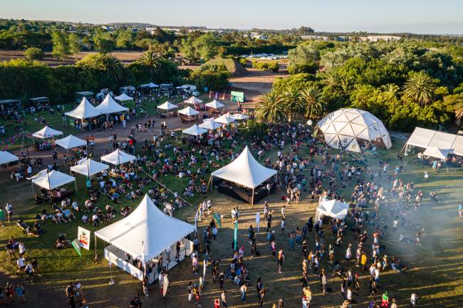 ExpoCannabis Um gramado com tendas e pessoas circulando