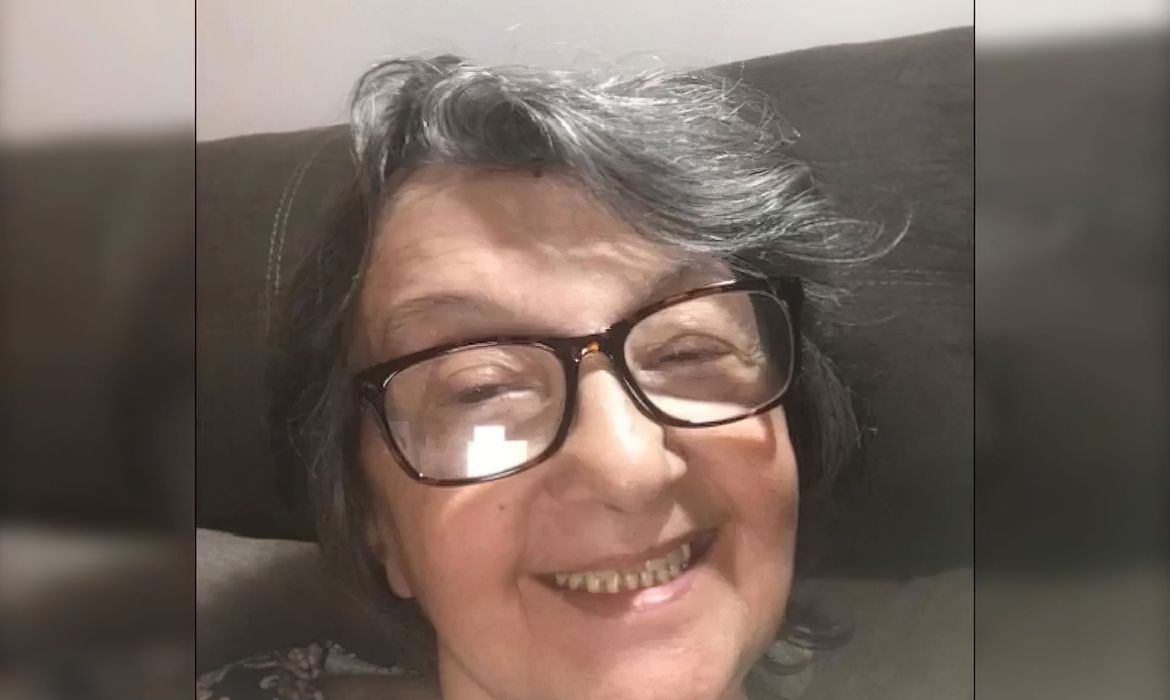 Senhora de óculos e cabelos grisalhos sorri em selfie.