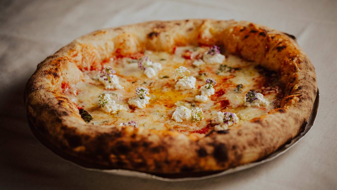 Pizza de borda alta sobre toalha de mesa branca.