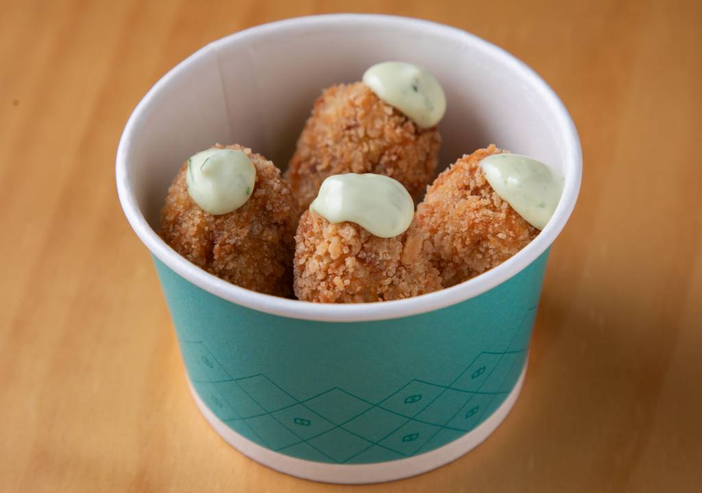 croquete de canjiquinha com costelinha _ Per Lui, _ feira comer e beber 2023 Pote azul redondo com quatro croquetes e molho em cima de cada um.