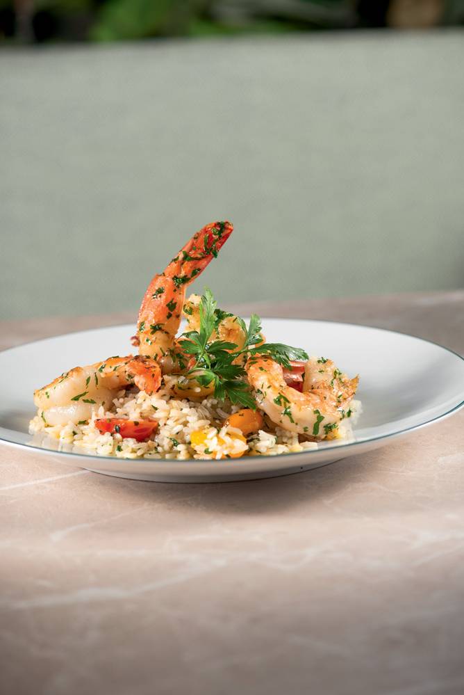 Les Deux Magots prato de louça branca com arroz com tomate coberto por camarão.
