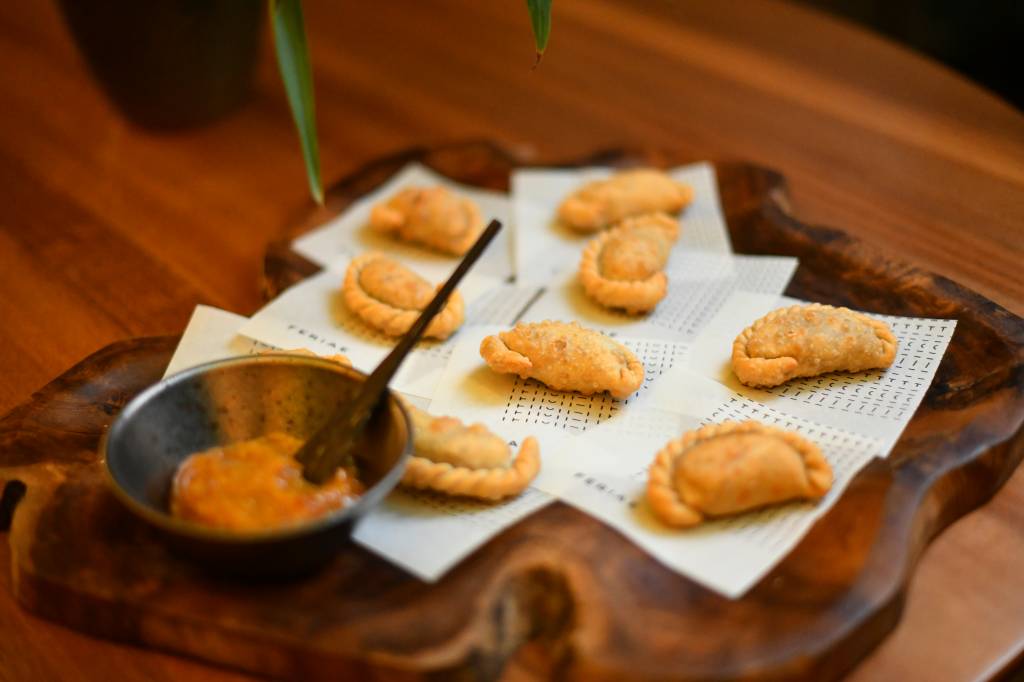 Jantar Circuito Comer & Beber pasteizinhos em cima de bandeja de madeira com tigela de madeira de chutney