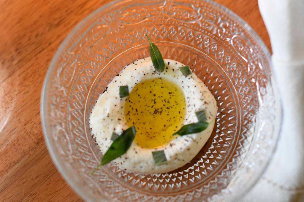 Jantar Circuito Comer & Beber tigela de vidro com sorvete branco coberto por azeite e sálvia