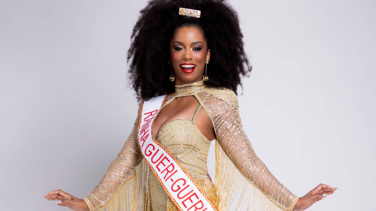 Mulher negra posa com as mãos estendidas vestindo roupa dourada e faixa "rainha do Gueri-Gueri"
