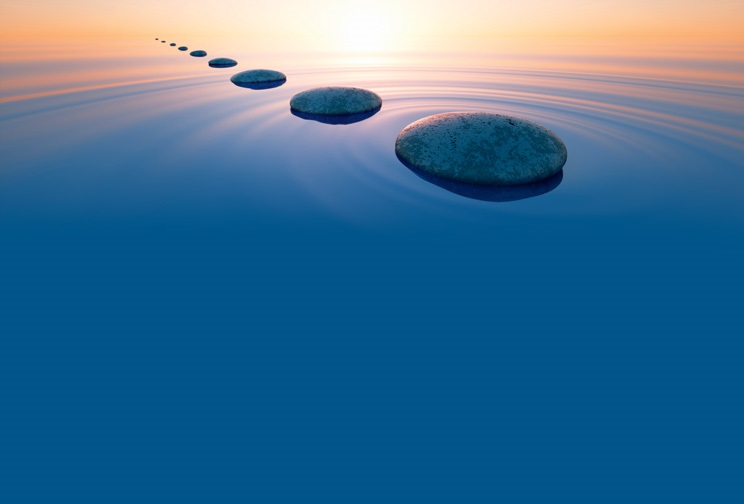 Row of dark stones in calm ocean with evening sun with horizon - tranquil scenery