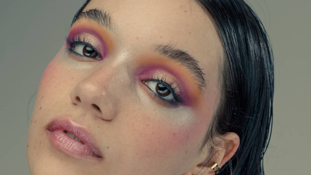 Adolescente branca com maquiagem colorida nos olhos e cabelos lisos escorridos