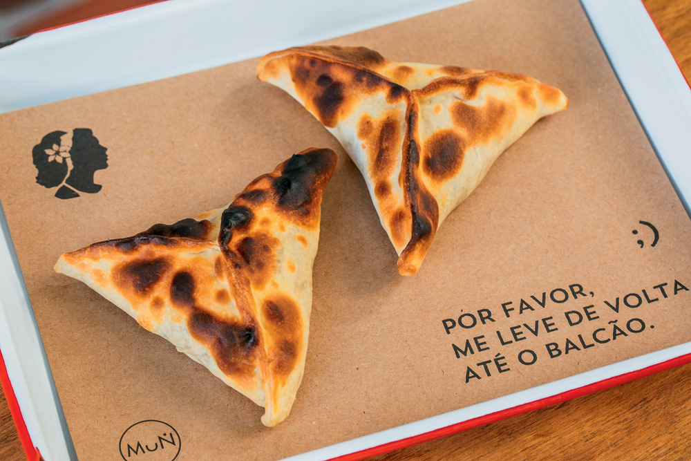 Esfirra e empanada em uma bandeja da La Guapa