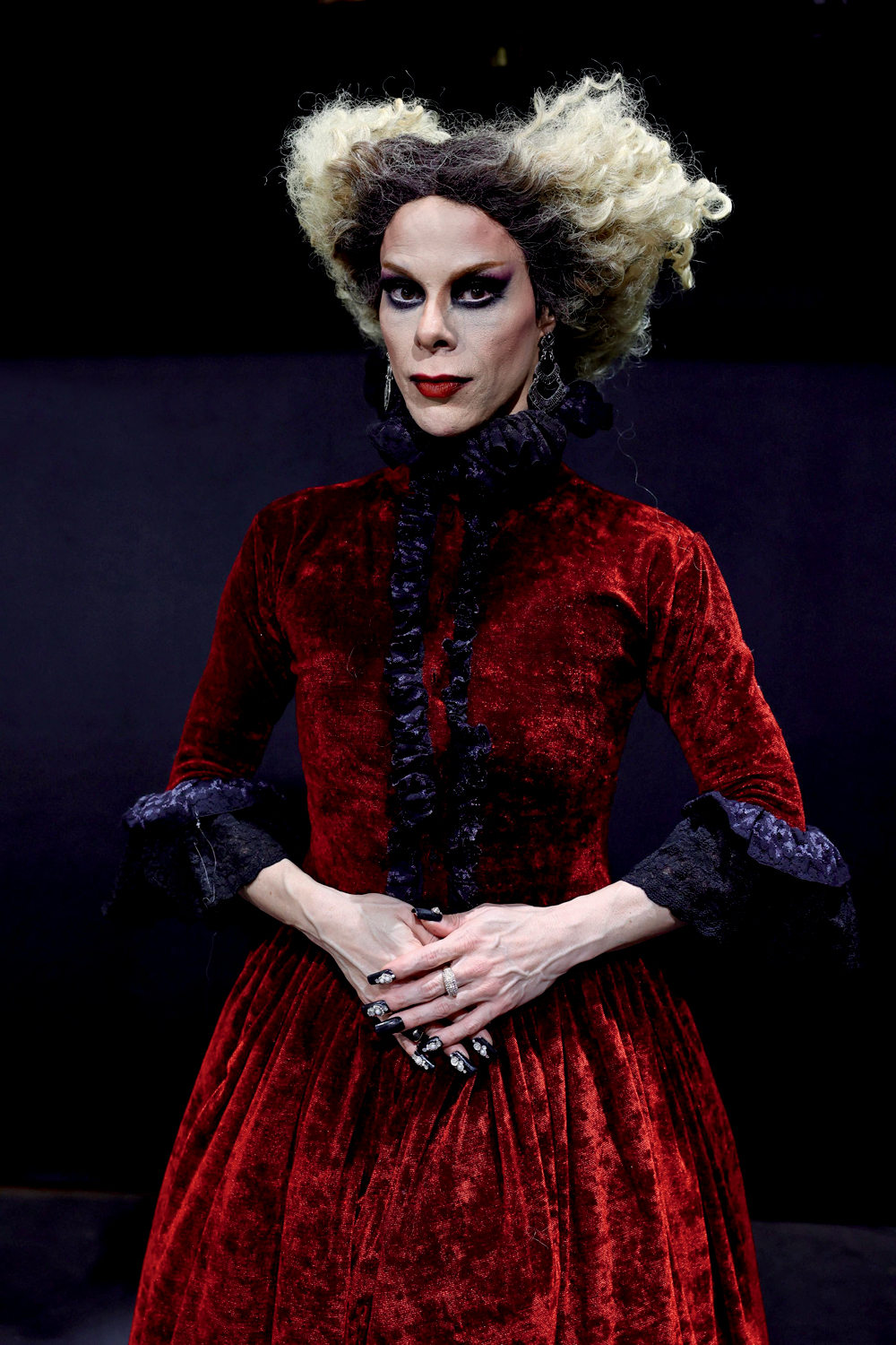 Alexia Twister-Crédito Tetembua Dandara-Divulgação (5).jpg Drag queen com maquiagem preta nos olhos, roupa preta e vermelha até o pescoço e cabelos loiros curtos espichados